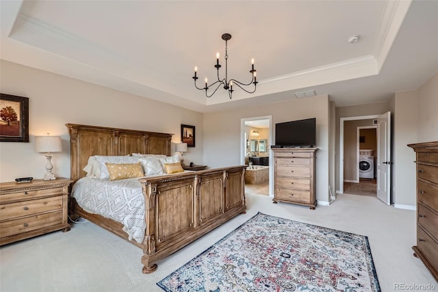 carpeted bedroom with a notable chandelier, a raised ceiling, washer / clothes dryer, and ensuite bath