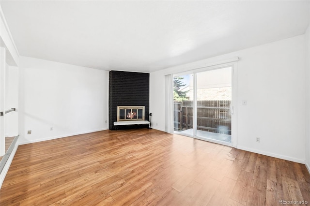 unfurnished living room with light hardwood / wood-style flooring and a brick fireplace