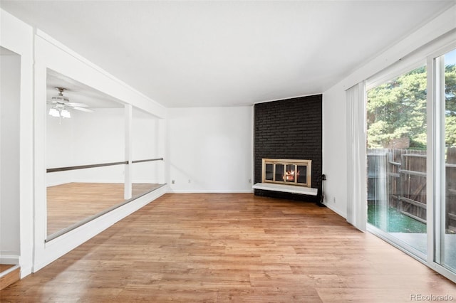 unfurnished living room featuring ceiling fan, light hardwood / wood-style floors, and a brick fireplace