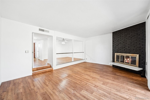 unfurnished living room with ceiling fan, a fireplace, and hardwood / wood-style flooring