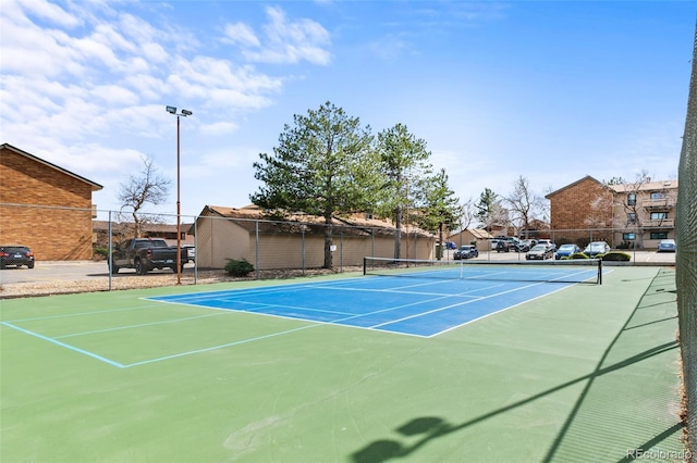 view of tennis court with a residential view, fence, and community basketball court