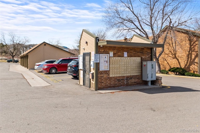 view of community with uncovered parking and mail area