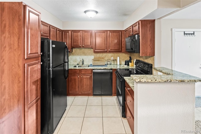 kitchen featuring a peninsula, a sink, light stone countertops, black appliances, and backsplash