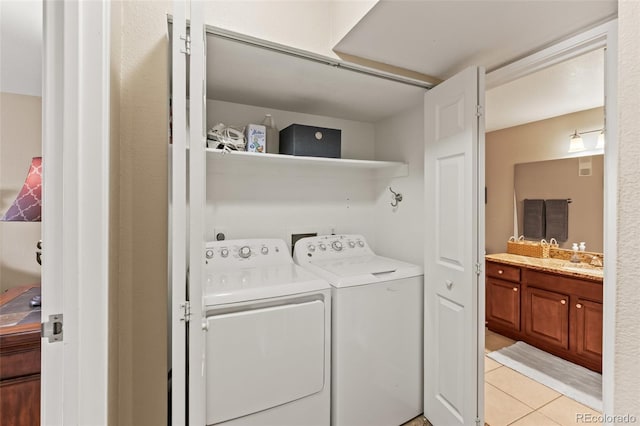 clothes washing area featuring washing machine and clothes dryer, laundry area, light tile patterned flooring, and a sink