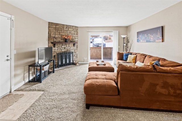 carpeted living area with baseboards and a stone fireplace