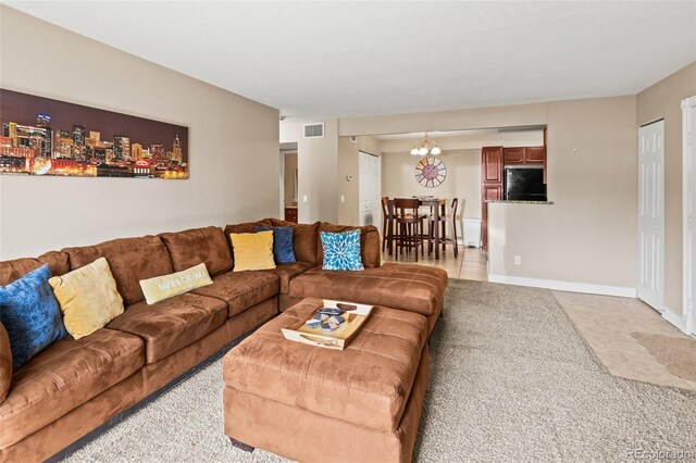 living area featuring a chandelier, visible vents, baseboards, and light carpet