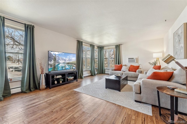 living area with a baseboard radiator, an AC wall unit, and wood finished floors