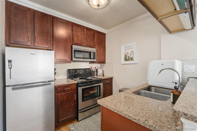 kitchen with stainless steel appliances, tasteful backsplash, a sink, and light stone counters