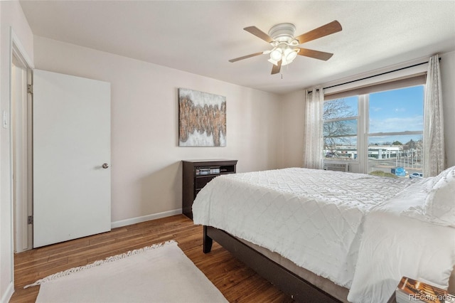 bedroom featuring a ceiling fan, baseboards, and wood finished floors