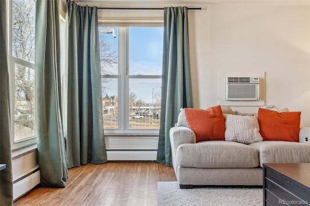 sitting room with a baseboard heating unit, light wood-style flooring, and a wall mounted AC