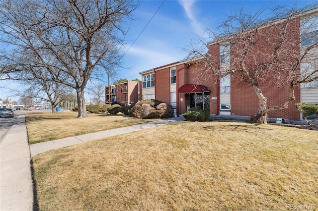 exterior space with brick siding and a front lawn