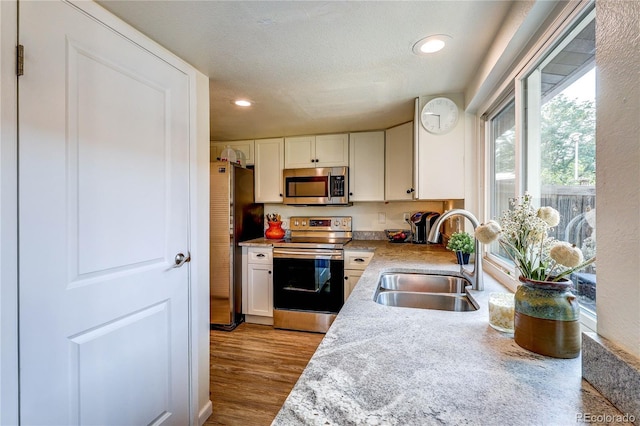 3572 S Kittredge St Unit B, Aurora, CO 80013 - kitchen with stainless steel appliances, white cabinetry, light countertops, recessed lighting, and wood finished floors