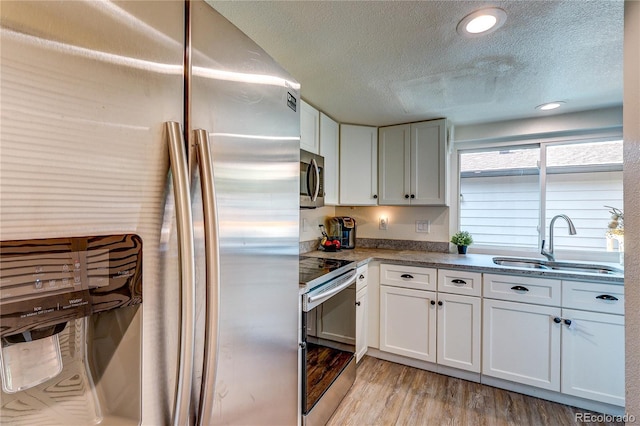 3572 S Kittredge St Unit B, Aurora, CO 80013 - kitchen featuring stainless steel appliances, a textured ceiling, white cabinetry, and light wood-style floors