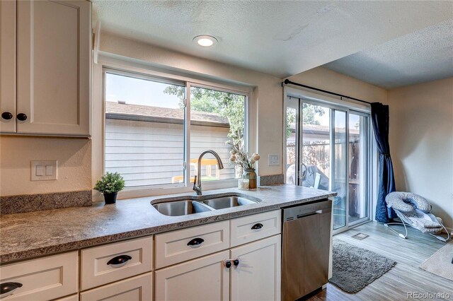 3572 S Kittredge St Unit B, Aurora, CO 80013 - kitchen with stainless steel dishwasher, a textured ceiling, wood finished floors, and white cabinets