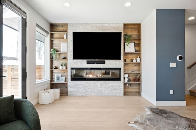 living room featuring hardwood / wood-style floors, wooden walls, and a stone fireplace