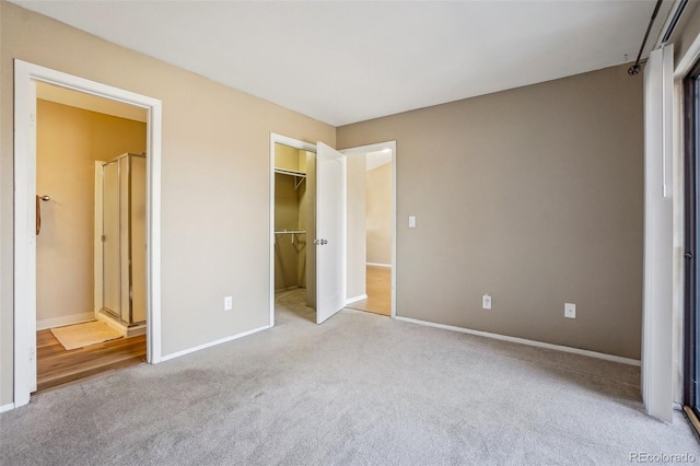 unfurnished bedroom with a spacious closet, a closet, and light carpet