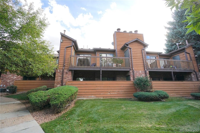 rear view of house with a balcony and a yard