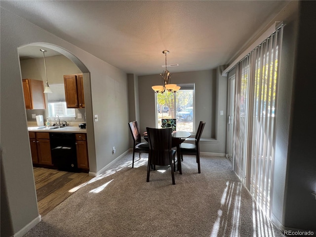 dining room featuring a textured ceiling, dark wood-type flooring, sink, and an inviting chandelier