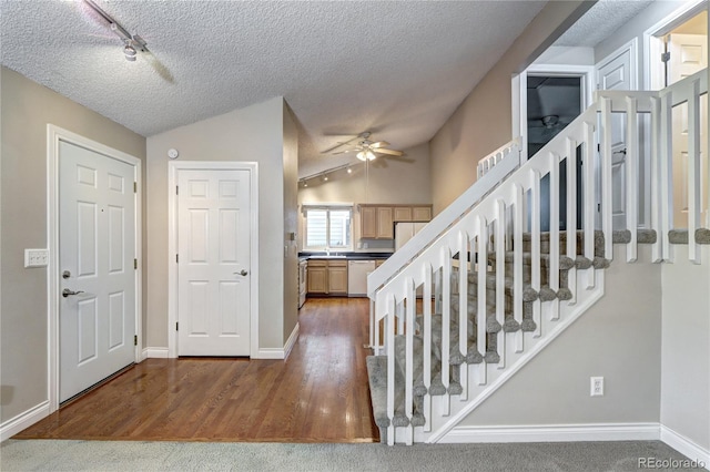 stairway with vaulted ceiling, hardwood / wood-style floors, a textured ceiling, sink, and ceiling fan