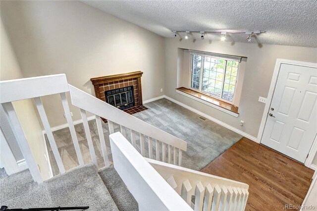 interior space with a fireplace, wood-type flooring, a textured ceiling, and vaulted ceiling