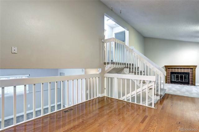 staircase with a textured ceiling, hardwood / wood-style flooring, and plenty of natural light