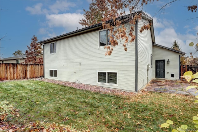 rear view of house featuring a lawn and a patio