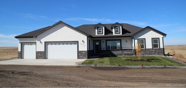 view of front of property featuring stone siding, stucco siding, an attached garage, and concrete driveway