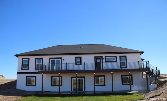 rear view of property with a lawn and stucco siding