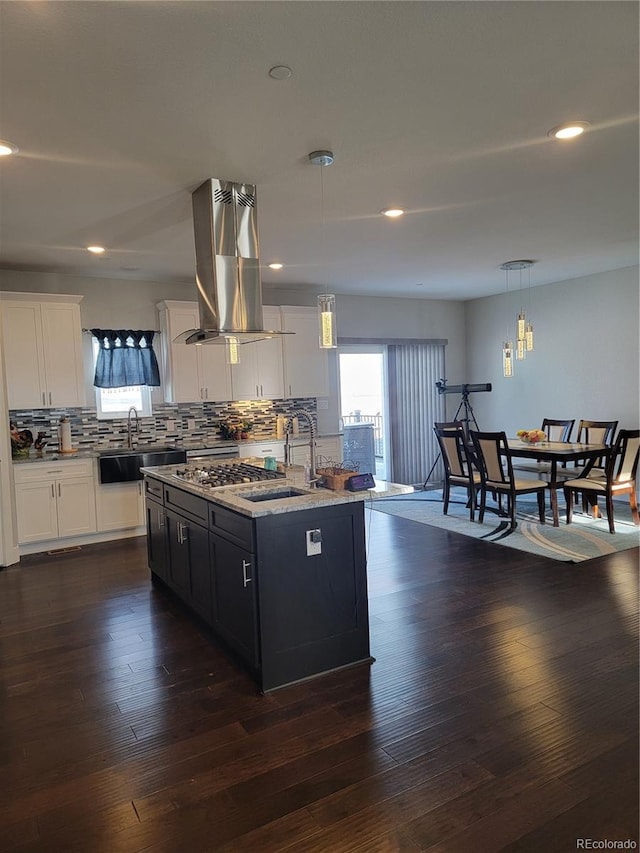 kitchen featuring hanging light fixtures, a sink, white cabinets, and a center island