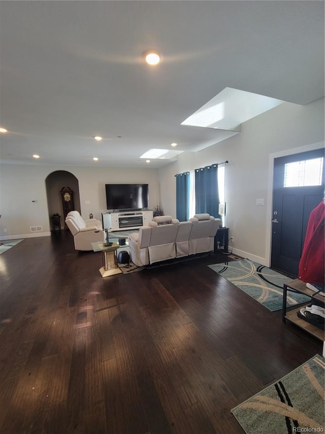 living room with arched walkways, recessed lighting, visible vents, wood finished floors, and baseboards