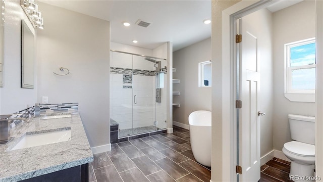 full bath featuring double vanity, toilet, a sink, a shower stall, and baseboards