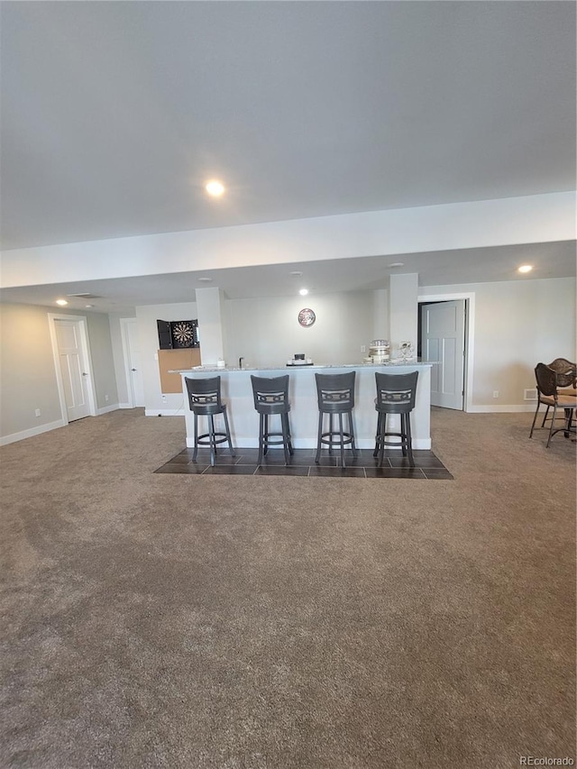 dining space with bar area, baseboards, dark colored carpet, and recessed lighting