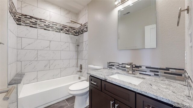 bathroom featuring visible vents, a textured wall, toilet, vanity, and  shower combination