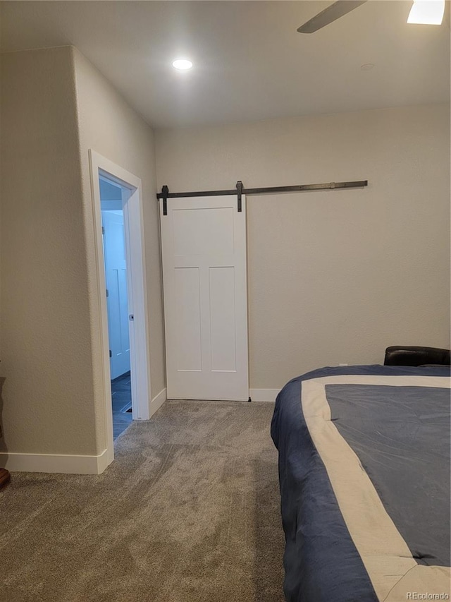 bedroom with carpet floors, recessed lighting, baseboards, and a barn door