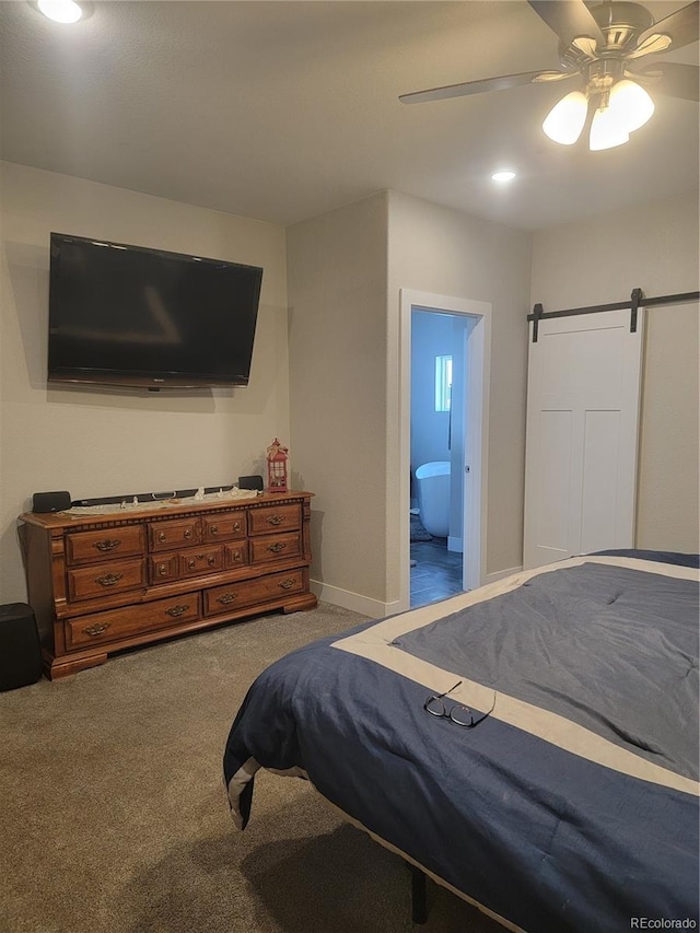 carpeted bedroom featuring a ceiling fan, baseboards, ensuite bathroom, and a barn door