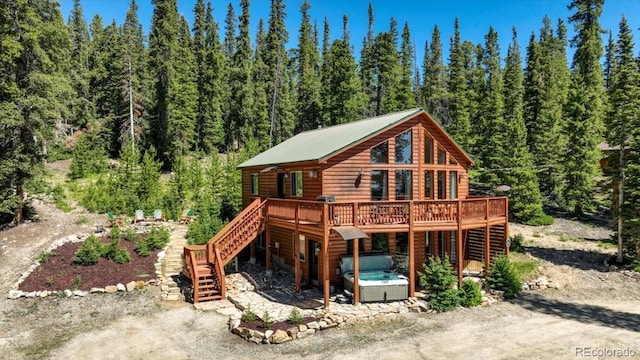 1387 Bobcat Ln, Fairplay, CO 80440 - rear view of house with a hot tub, a deck, stairway, a view of trees, and faux log siding