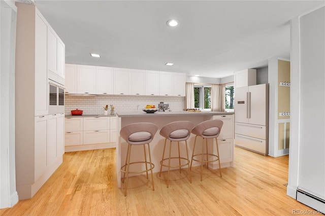 350 Tower Hill Cir, Golden, CO 80401 - kitchen with white appliances, light wood-type flooring, a breakfast bar, decorative backsplash, and white cabinetry
