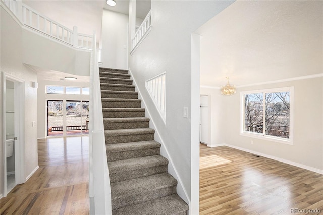 stairs with a chandelier, plenty of natural light, and wood-type flooring