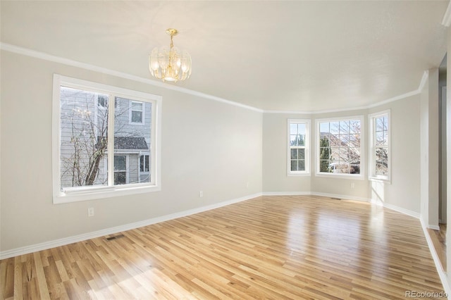 unfurnished room featuring ornamental molding, light wood-type flooring, and an inviting chandelier