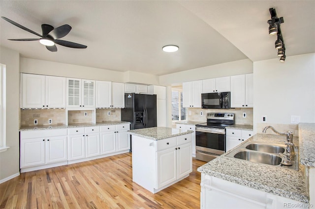 kitchen featuring ceiling fan, sink, a kitchen island, white cabinets, and black appliances