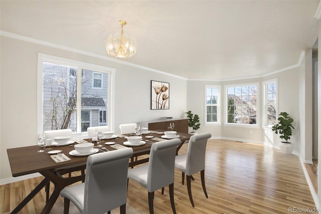 dining room with an inviting chandelier, light hardwood / wood-style flooring, and crown molding