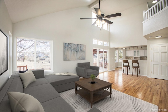 living room featuring beam ceiling, ceiling fan, high vaulted ceiling, and light wood-type flooring