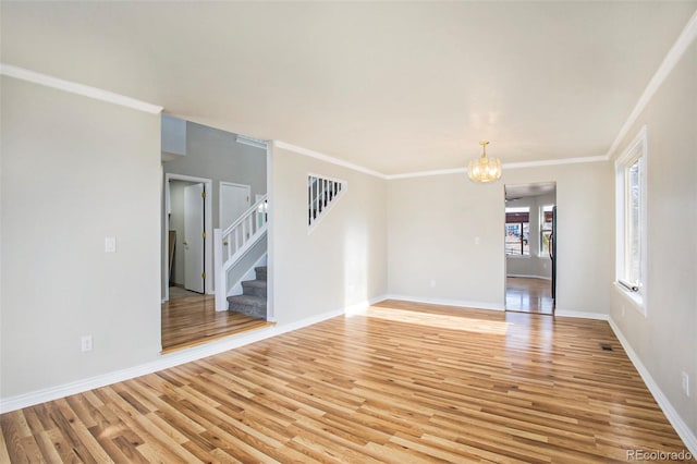 unfurnished room featuring light wood-type flooring, crown molding, and a chandelier