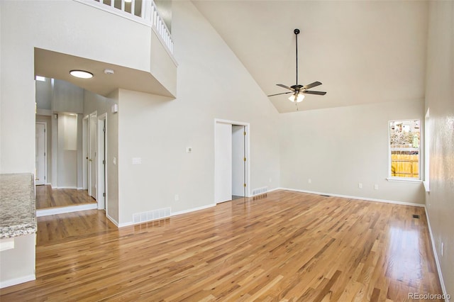 unfurnished living room with light hardwood / wood-style floors, high vaulted ceiling, and ceiling fan