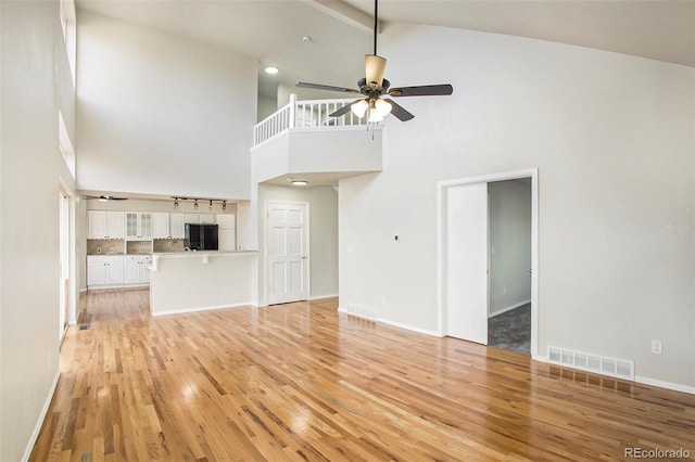 unfurnished living room featuring light hardwood / wood-style flooring, high vaulted ceiling, and ceiling fan