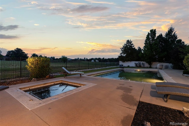 5653 Yank St, Arvada, CO 80002 - pool at dusk featuring an in-ground hot tub, a fenced backyard, and a patio