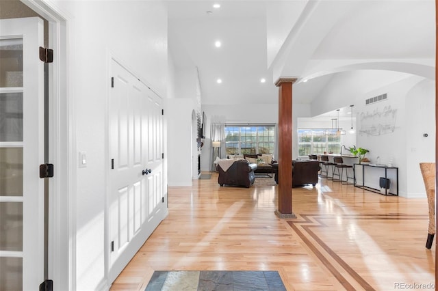 5653 Yank St, Arvada, CO 80002 - hall featuring decorative columns, light wood-style flooring, high vaulted ceiling, arched walkways, and recessed lighting