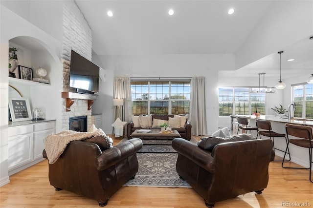 5653 Yank St, Arvada, CO 80002 - living area with a stone fireplace, light wood-type flooring, recessed lighting, and high vaulted ceiling