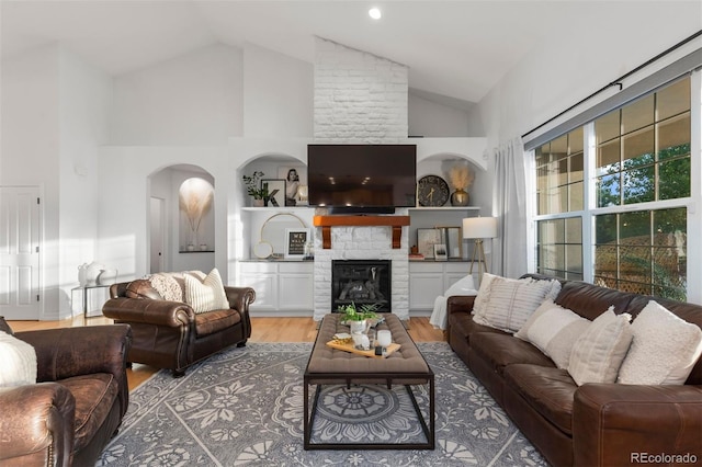 5653 Yank St, Arvada, CO 80002 - living area with high vaulted ceiling, light wood-style flooring, arched walkways, and a fireplace