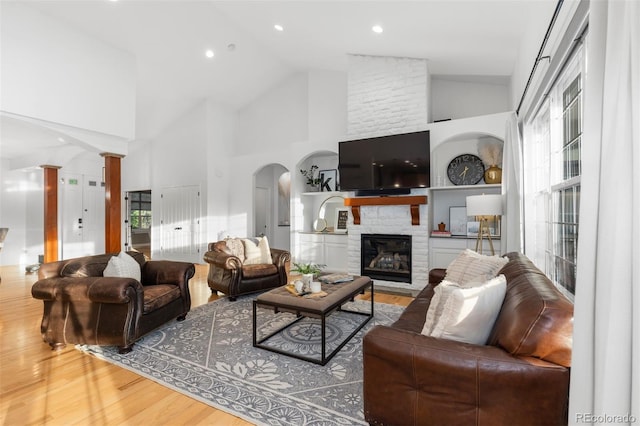 5653 Yank St, Arvada, CO 80002 - living room with wood finished floors, high vaulted ceiling, a fireplace, decorative columns, and recessed lighting